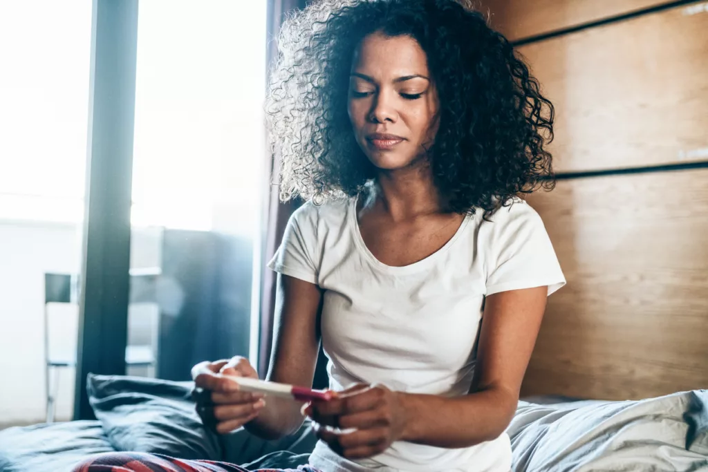 Sad young woman with pregnancy test concerned about endometriosis and fertility
