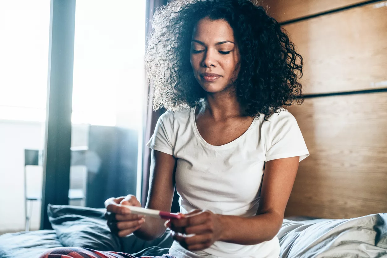 Sad young woman with pregnancy test concerned about endometriosis and fertility
