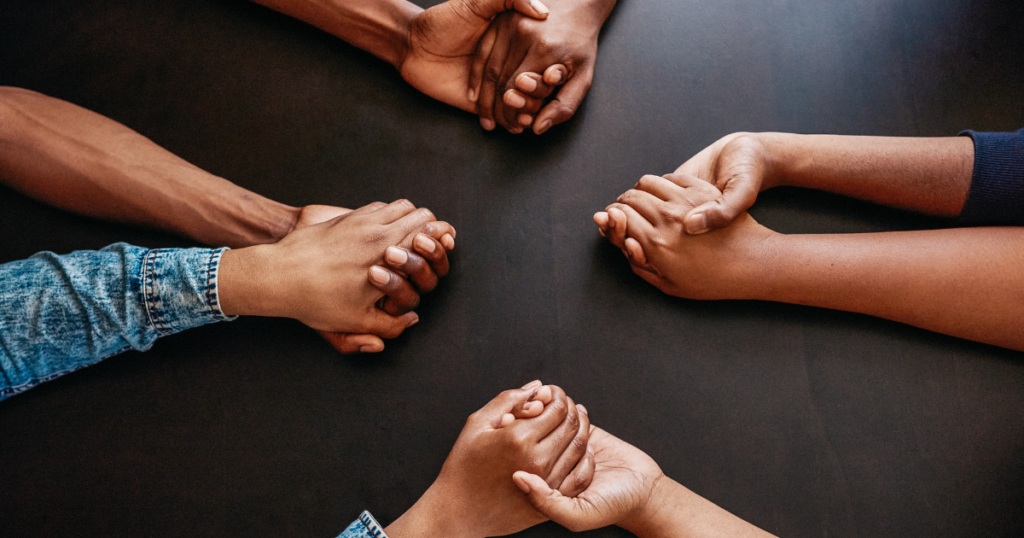 Close-up of multiple pairs of women holding hands in a circle, symbolizing unity, strength, and support—representing community and solidarity during Fibroids Awareness Month.