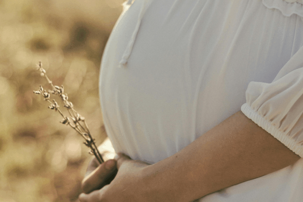 A serene close-up of a pregnant person in a flowing white dress holding dried wildflowers, symbolizing hope and new beginnings—capturing the spirit of World Fertility Day and Viva Eve’s commitment to compassionate fertility care and awareness.
