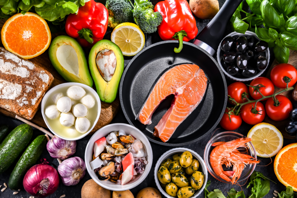 Overhead view of salmon, eggs, seafood, vegetables, avocado, citrus, and other nutrient-rich foods associated with a balanced diet that supports menopause health.