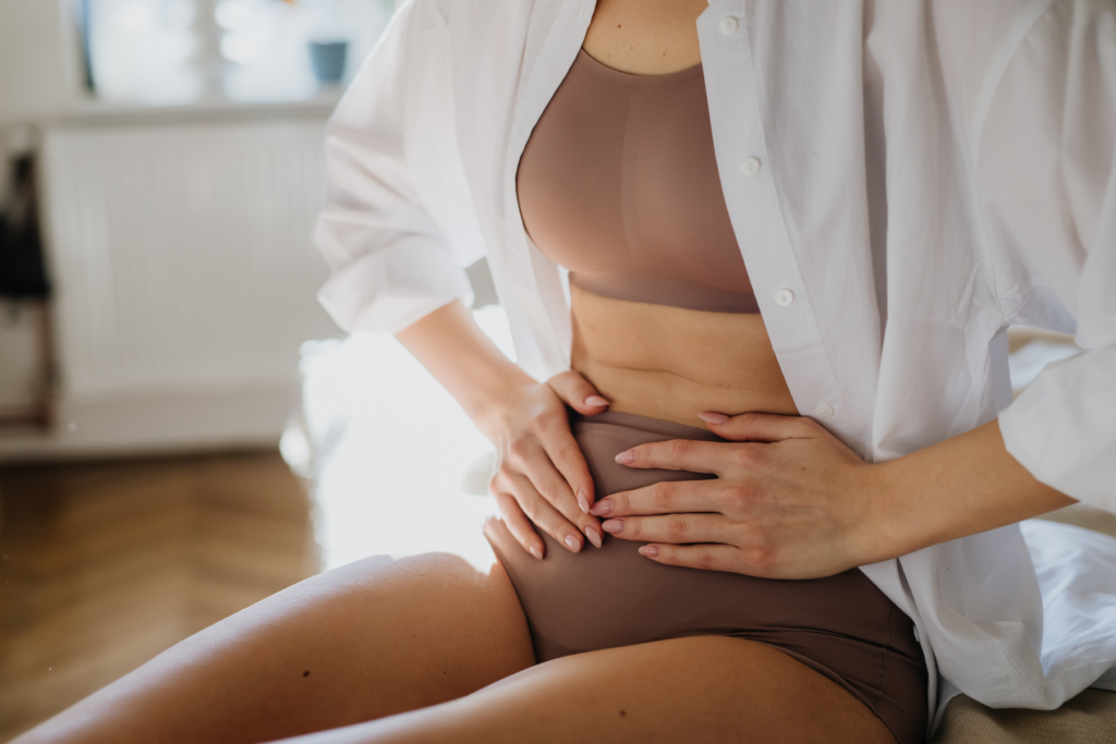 Woman holding her lower abdomen, illustrating pelvic pain that may be associated with endometriosis.